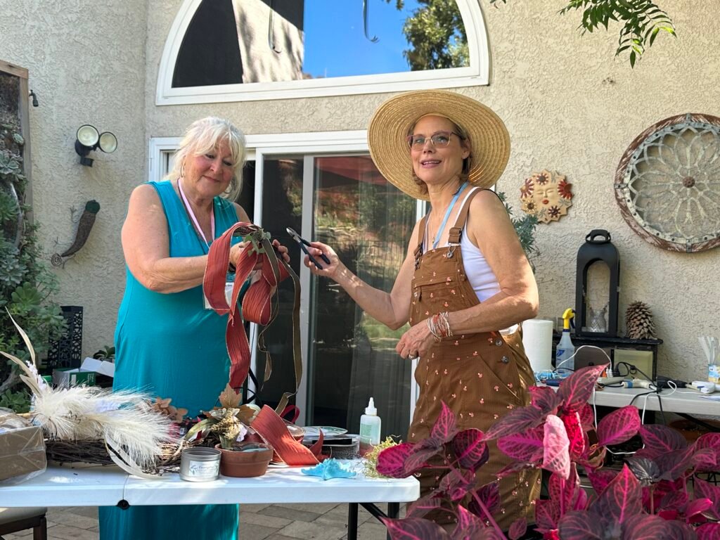 Laurie assists Susan as she shows the club how to assemble their wreaths